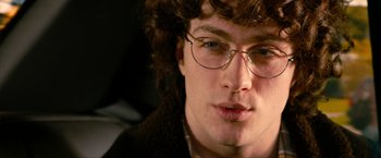 Movie still from “Kick-Ass 2” (2013), directed by Jeff Wadlow – A person wearing glasses and a jacket; Close Up shot, Over the shoulder angle