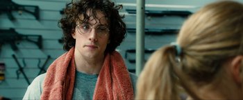 Movie still from “Kick-Ass 2” (2013), directed by Jeff Wadlow – A young man with glasses and a towel around his neck looks at a woman; Close Up shot, Over the shoulder angle