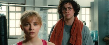 Movie still from “Kick-Ass 2” (2013), directed by Jeff Wadlow – A man and a woman standing next to each other in a room; Close Up shot, Low angle