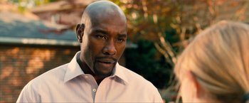 Movie still from “Kick-Ass 2” (2013), directed by Jeff Wadlow – A man with a bald head wearing a pink shirt; Close Up shot, Over the shoulder angle