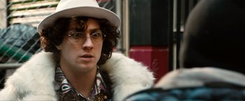 Movie still from “Kick-Ass 2” (2013), directed by Jeff Wadlow – A man in a hat and glasses looking at the camera; Close Up shot, Over the shoulder angle