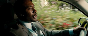 Movie still from “Kick-Ass 2” (2013), directed by Jeff Wadlow – A man in a suit and tie driving a car; Close Up shot, High angle