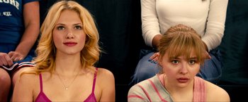 Movie still from “Kick-Ass 2” (2013), directed by Jeff Wadlow – Two women sitting next to each other in front of a wall; Close Up shot, Over the shoulder angle