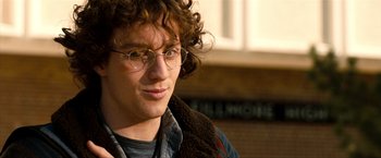 Movie still from “Kick-Ass 2” (2013), directed by Jeff Wadlow – A young man wearing glasses and a brown jacket; Close Up shot, Low angle