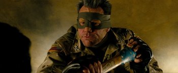 Movie still from “Kick-Ass 2” (2013), directed by Jeff Wadlow – A man in a military uniform with a mask on his face and holding a baseball bat; Close Up shot, Overhead angle