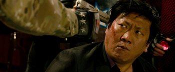 Movie still from “Kick-Ass 2” (2013), directed by Jeff Wadlow – A man with a gun pointed at him in a dark room; Close Up shot, Over the shoulder angle