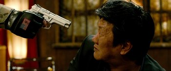Movie still from “Kick-Ass 2” (2013), directed by Jeff Wadlow – A man is holding a gun up to his face; Close Up shot, Over the shoulder angle