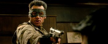 Movie still from “Kick-Ass 2” (2013), directed by Jeff Wadlow – A man with a gun wearing a mask and holding a gun in his hand; Close Up shot, Low angle
