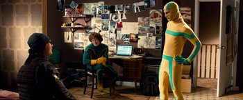 Movie still from “Kick-Ass 2” (2013), directed by Jeff Wadlow – A man sitting at a desk in front of a computer; Wide shot, Over the shoulder angle