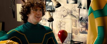 Movie still from “Kick-Ass 2” (2013), directed by Jeff Wadlow – A man with curly hair and glasses is smiling; Close Up shot, Over the shoulder angle