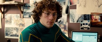Movie still from “Kick-Ass 2” (2013), directed by Jeff Wadlow – A man with curly brown hair wearing glasses and a green shirt; Close Up shot, Low angle