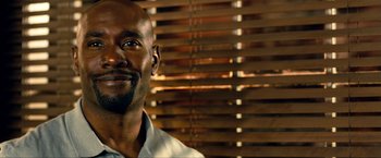 Movie still from “Kick-Ass 2” (2013), directed by Jeff Wadlow – A person wearing a white shirt near a window; Close Up shot, Low angle