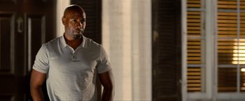 Movie still from “Kick-Ass 2” (2013), directed by Jeff Wadlow – A man in a white shirt is standing in front of a window; Medium shot, Over the shoulder angle