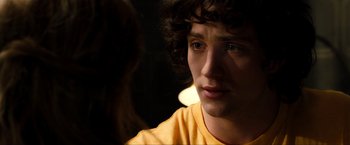Movie still from “Kick-Ass 2” (2013), directed by Jeff Wadlow – A young man with curly brown hair stares into the camera; Close Up shot, Over the shoulder angle