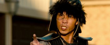 Movie still from “Kick-Ass 2” (2013), directed by Jeff Wadlow – A man in a black and gold outfit with a black hat; Close Up shot, Low angle