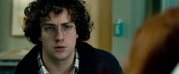 Movie still from “Kick-Ass 2” (2013), directed by Jeff Wadlow – A person wearing glasses and a jacket; Close Up shot, Over the shoulder angle