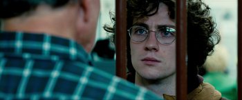 Movie still from “Kick-Ass 2” (2013), directed by Jeff Wadlow – A young man wearing glasses looking at the camera; Close Up shot, Over the shoulder angle