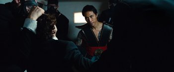 Movie still from “Kick-Ass 2” (2013), directed by Jeff Wadlow – A man with a tattoo on his chest is standing next to another man; Close Up shot, Over the shoulder angle