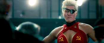 Movie still from “Kick-Ass 2” (2013), directed by Jeff Wadlow – A woman in a red and yellow outfit with a red and yellow symbol on it's chest; Close Up shot, Low angle