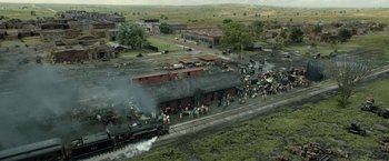 Movie still from “Killers of the Flower Moon” (2023), directed by Martin Scorsese – An aerial view of a train station with people on the tracks; Extreme Wide shot, High angle