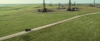 Movie still from “Killers of the Flower Moon” (2023), directed by Martin Scorsese – An aerial view of an oil field with a truck driving down the road; Extreme Wide shot, High angle