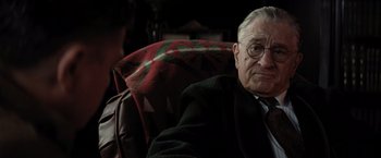 Movie still from “Killers of the Flower Moon” (2023), directed by Martin Scorsese – An older man sitting in a chair wearing glasses; Close Up shot, Over the shoulder angle