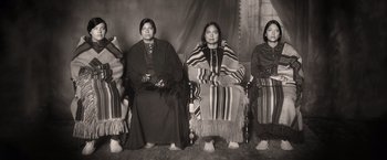 Movie still from “Killers of the Flower Moon” (2023), directed by Martin Scorsese – A group of native american women sitting on chairs; Wide shot, High angle