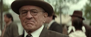 Movie still from “Killers of the Flower Moon” (2023), directed by Martin Scorsese – An old man wearing a hat and glasses; Close Up shot, Over the shoulder angle