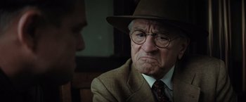 Movie still from “Killers of the Flower Moon” (2023), directed by Martin Scorsese – An older man wearing a hat and glasses; Close Up shot, Over the shoulder angle