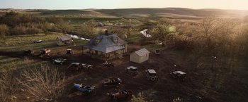 Movie still from “Killers of the Flower Moon” (2023), directed by Martin Scorsese – An aerial view of an old fashioned house with cars parked on the side of the road; Extreme Wide shot, High angle