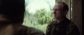 An older man is looking out a window