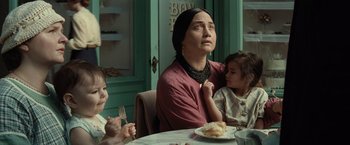 Movie still from “Killers of the Flower Moon” (2023), directed by Martin Scorsese – A woman sitting at a table with two small children; Medium shot, Over the shoulder angle