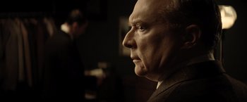 Movie still from “Killers of the Flower Moon” (2023), directed by Martin Scorsese – An older man in a suit looking into the distance; Close Up shot, Over the shoulder angle