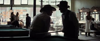 Movie still from “Killers of the Flower Moon” (2023), directed by Martin Scorsese – Two men are talking in front of a pool table; Medium shot, Over the shoulder angle