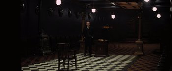 Movie still from “Killers of the Flower Moon” (2023), directed by Martin Scorsese – A man in a suit standing in front of a desk; Wide shot, High angle
