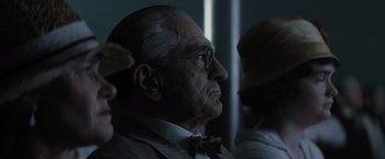 Movie still from “Killers of the Flower Moon” (2023), directed by Martin Scorsese – An old man wearing glasses and a bow tie; Close Up shot, Over the shoulder angle