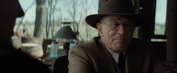 Movie still from “Killers of the Flower Moon” (2023), directed by Martin Scorsese – An older man wearing a hat and glasses; Close Up shot, Over the shoulder angle