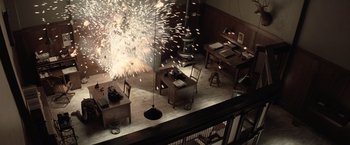 Movie still from “Killers of the Flower Moon” (2023), directed by Martin Scorsese – A room filled with tables and chairs and a bunch of fireworks in the background; Extreme Wide shot, Overhead angle