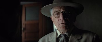 Movie still from “Killers of the Flower Moon” (2023), directed by Martin Scorsese – An older man wearing a hat and glasses; Close Up shot, Over the shoulder angle