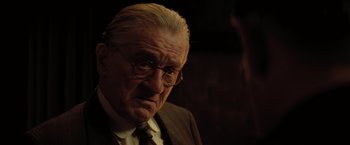 Movie still from “Killers of the Flower Moon” (2023), directed by Martin Scorsese – An old man with a beard wearing a suit and tie; Close Up shot, Over the shoulder angle