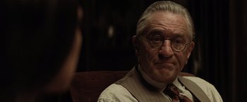 Movie still from “Killers of the Flower Moon” (2023), directed by Martin Scorsese – An old man with glasses sitting in a chair; Close Up shot, Over the shoulder angle