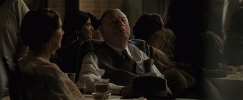 Movie still from “Killers of the Flower Moon” (2023), directed by Martin Scorsese – An older man sitting at a table with his eyes closed; Medium shot, Over the shoulder angle