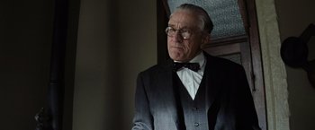 Movie still from “Killers of the Flower Moon” (2023), directed by Martin Scorsese – An older man in a suit and bow tie; Close Up shot, Low angle