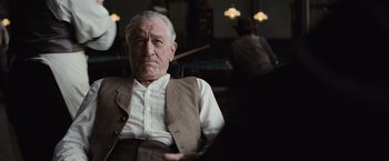 Movie still from “Killers of the Flower Moon” (2023), directed by Martin Scorsese – An older man sitting in front of a piano in a room; Close Up shot, Over the shoulder angle