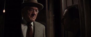 Movie still from “Killers of the Flower Moon” (2023), directed by Martin Scorsese – An older man wearing a hat and glasses; Close Up shot, Over the shoulder angle