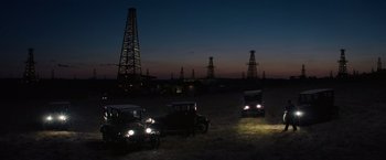 Movie still from “Killers of the Flower Moon” (2023), directed by Martin Scorsese – An oil field at night with old cars parked in the foreground; Extreme Wide shot, High angle