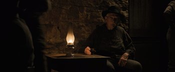 Movie still from “Killers of the Flower Moon” (2023), directed by Martin Scorsese – An old man sitting in front of an oil lamp; Medium shot, Low angle