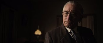 Movie still from “Killers of the Flower Moon” (2023), directed by Martin Scorsese – An older man wearing glasses and a suit and tie; Close Up shot, Over the shoulder angle