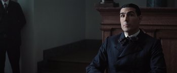 Movie still from “Killers of the Flower Moon” (2023), directed by Martin Scorsese – A man sitting in a chair wearing a suit and tie; Close Up shot, Over the shoulder angle