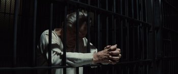 Movie still from “Killers of the Flower Moon” (2023), directed by Martin Scorsese – An old man in a jail cell with his hands clasped together; Medium shot, High angle